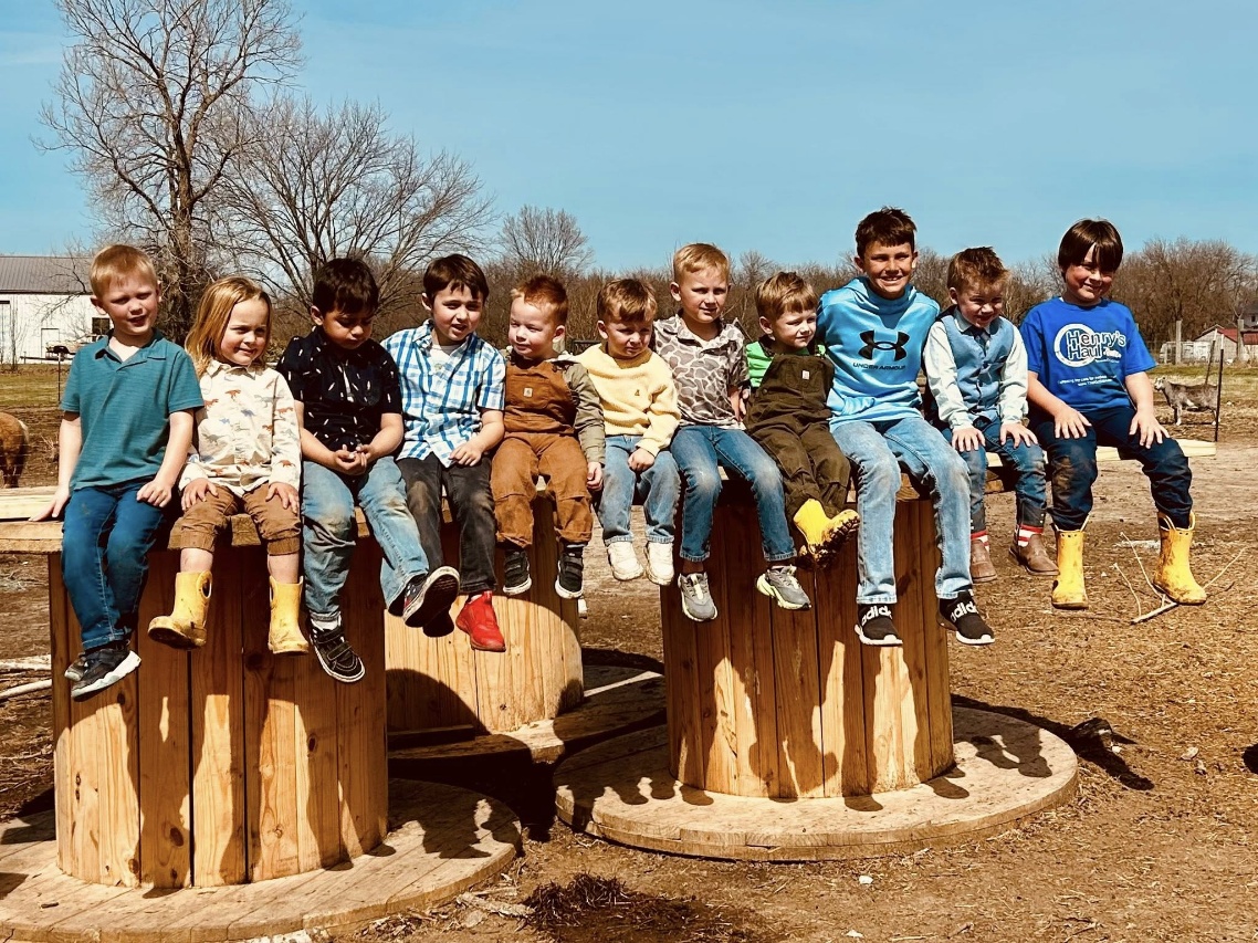 Group of Farmschool kids sitting together on wooden stumps