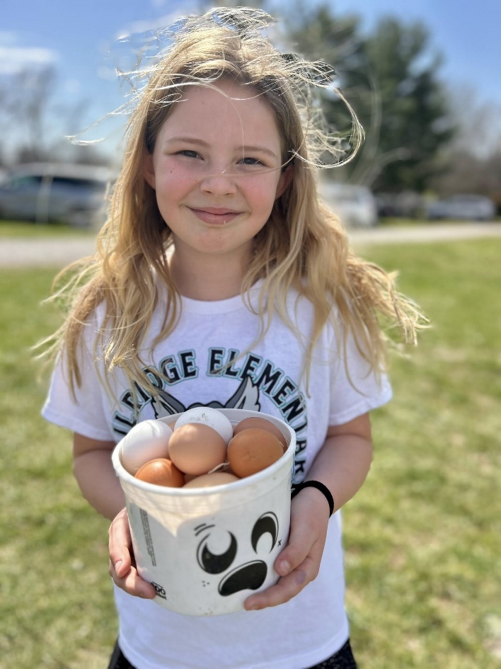 Young girl proudly holding a bucket of freshly collected eggs